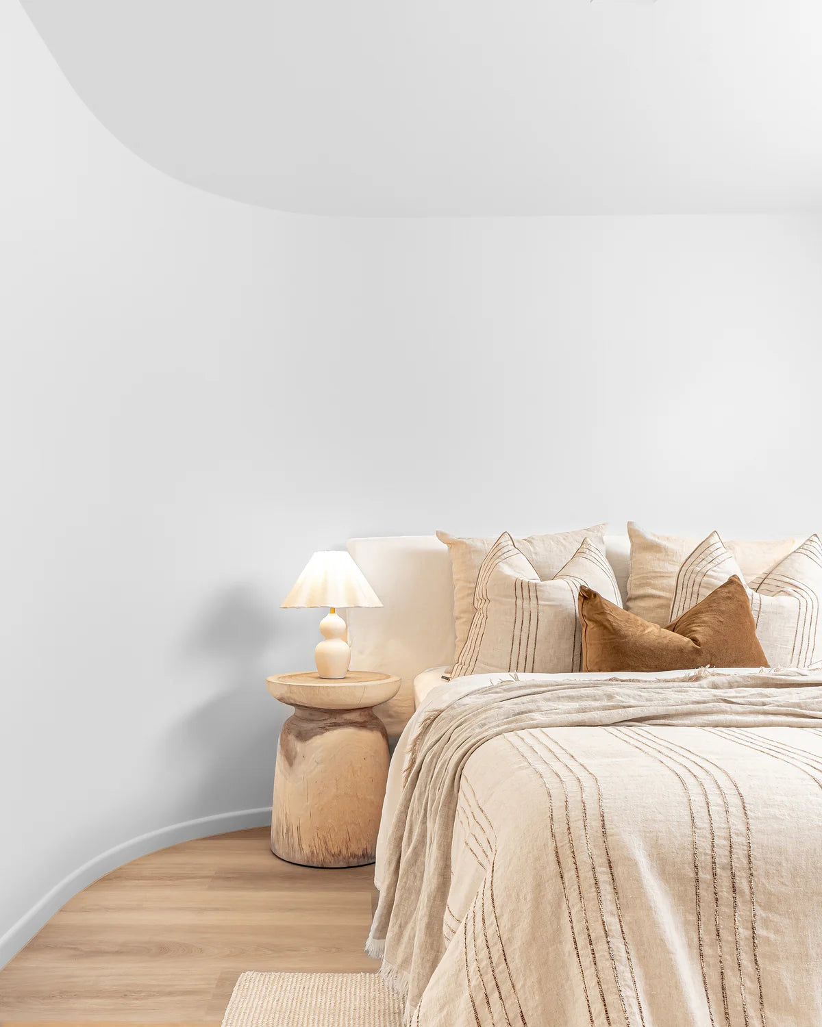Akoni Side Table – hand-carved munggur wood side table with smooth sanded finish, unique natural design crafted using traditional techniques. Styled beautifully in this modern bedroom.