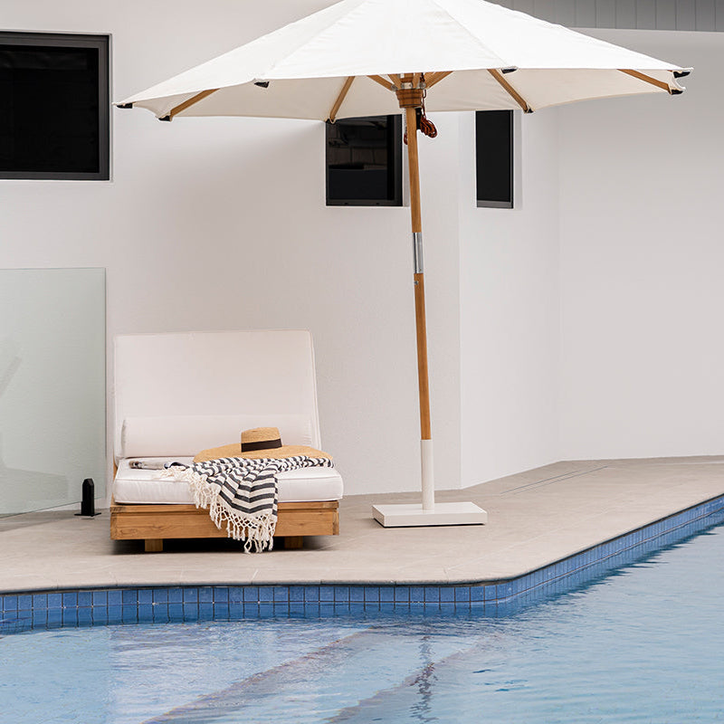 Amalfi Outdoor Umbrella Base supporting a premium outdoor umbrella beside a luxury swimming pool.