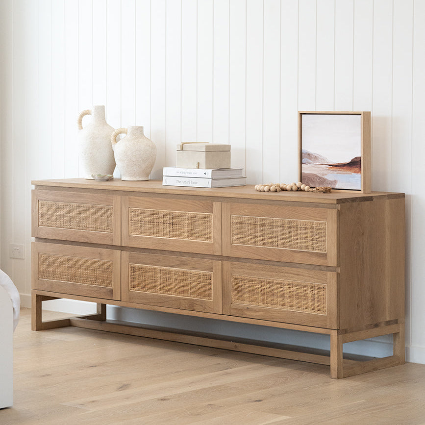 Beach House oak and rattan chest against white wall panelling with decorative ceramics