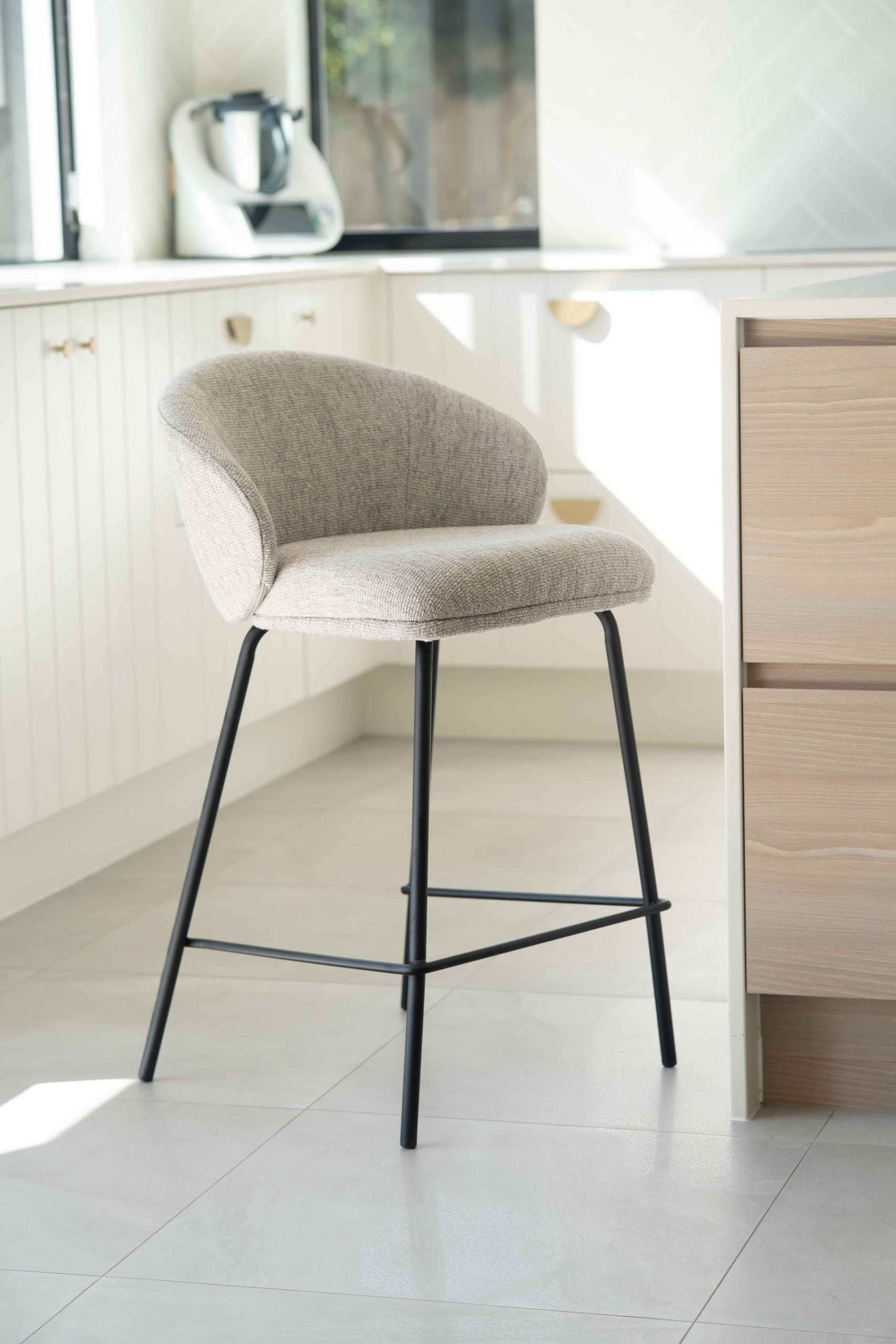 Bellevue Counter Stool with padded Pebble fabric seat and back, slim black powder-coated steel frame, modern elegant design. Beautifully styled in this modern home.