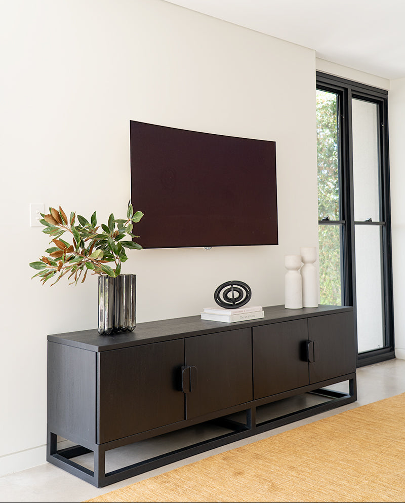 Benji 2m black teak entertainment unit styled beneath artwork beside a window, portrait living room view
