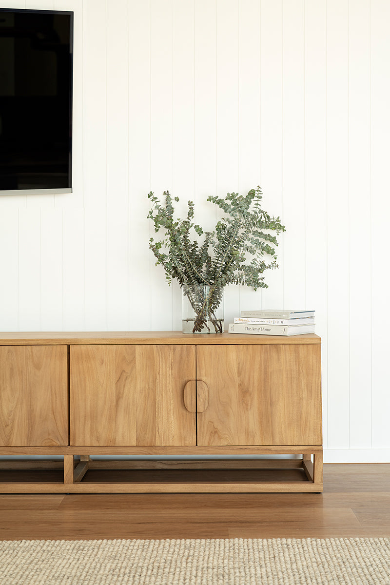 Benji 3m natural teak entertainment unit styled below a wall-mounted television with a vase and books, portrait view