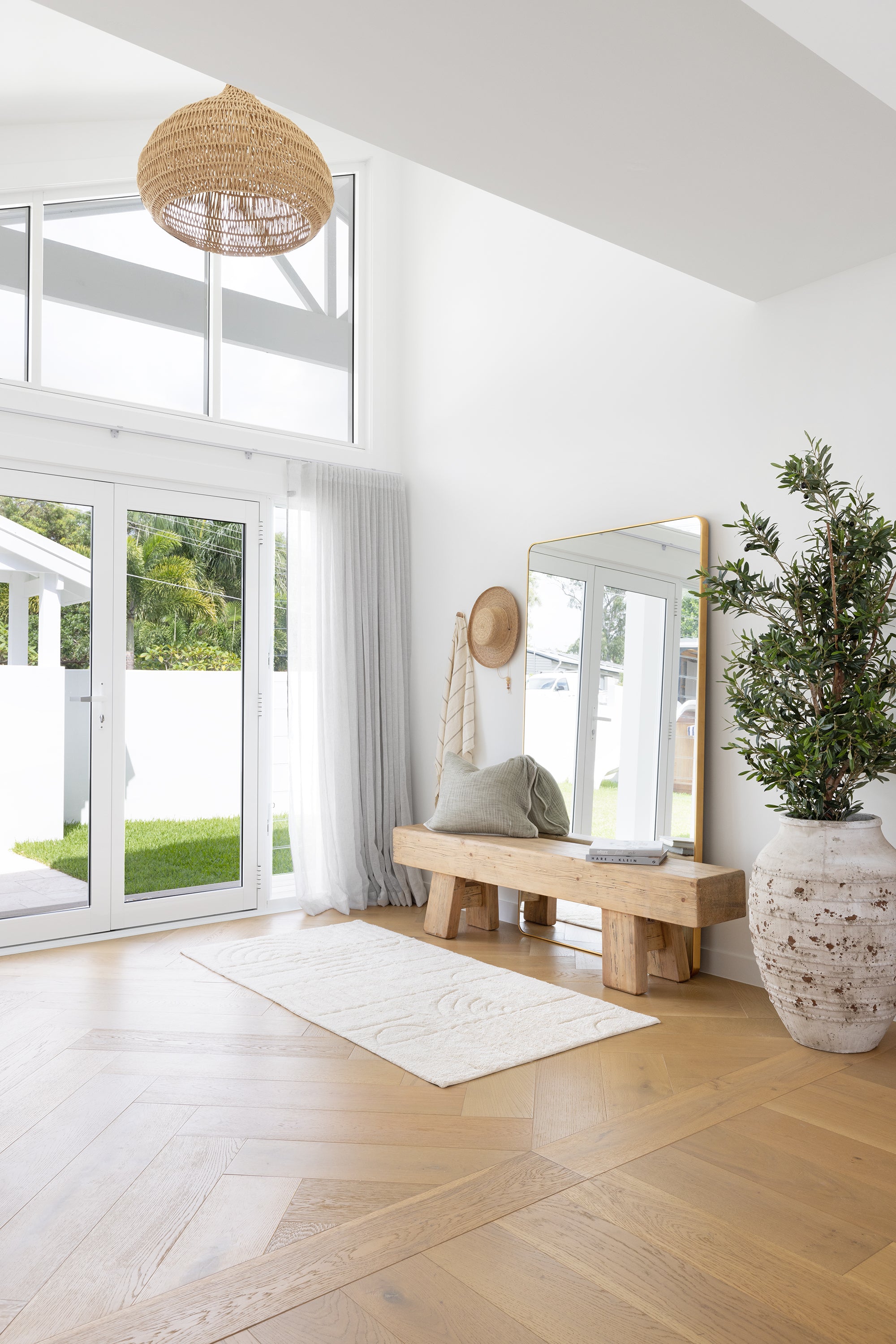 Natural cotton bath runner styled in entryway as soft rug beneath timber bench with glass doors and natural light