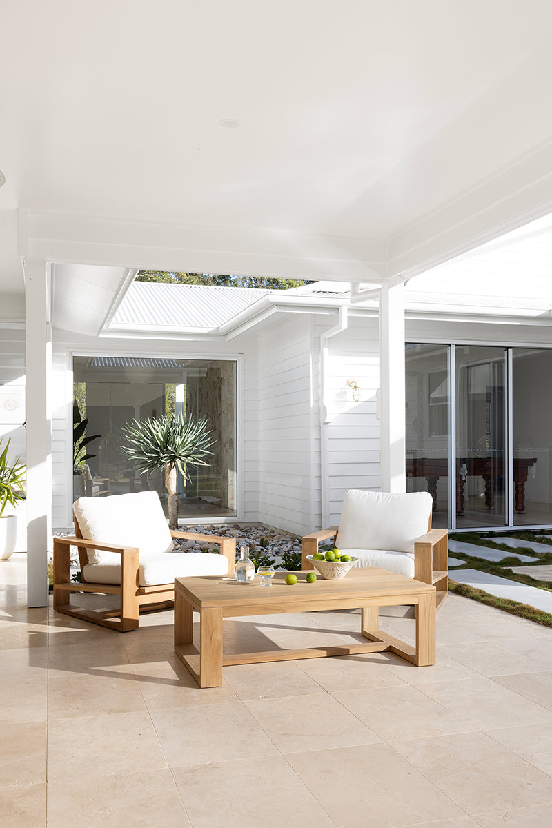Teak coffee table styled with outdoor lounge seating on a covered patio