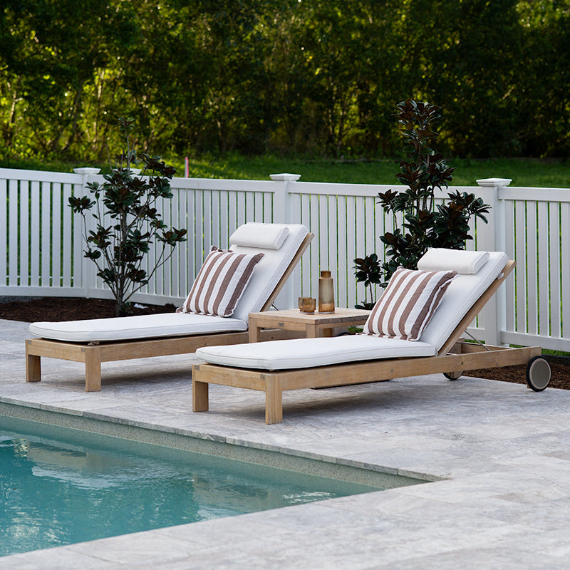 Harbour Island Slim Outdoor Sun Lounger crafted from Grade A teak with white Sunbrella® cushions beside a luxury swimming pool.