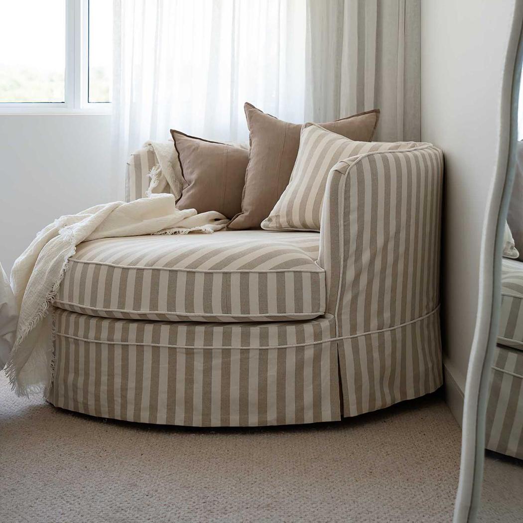 Noosa snuggle occasional chair in Natural Stripe with White Piping, styled with cushions and a side table in a living room