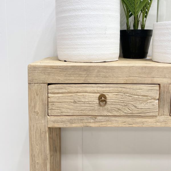 Reclaimed timber console table with four drawers and brass-look metal handles, handcrafted coastal furniture combining rustic and contemporary design for a warm, natural interior. Close up.