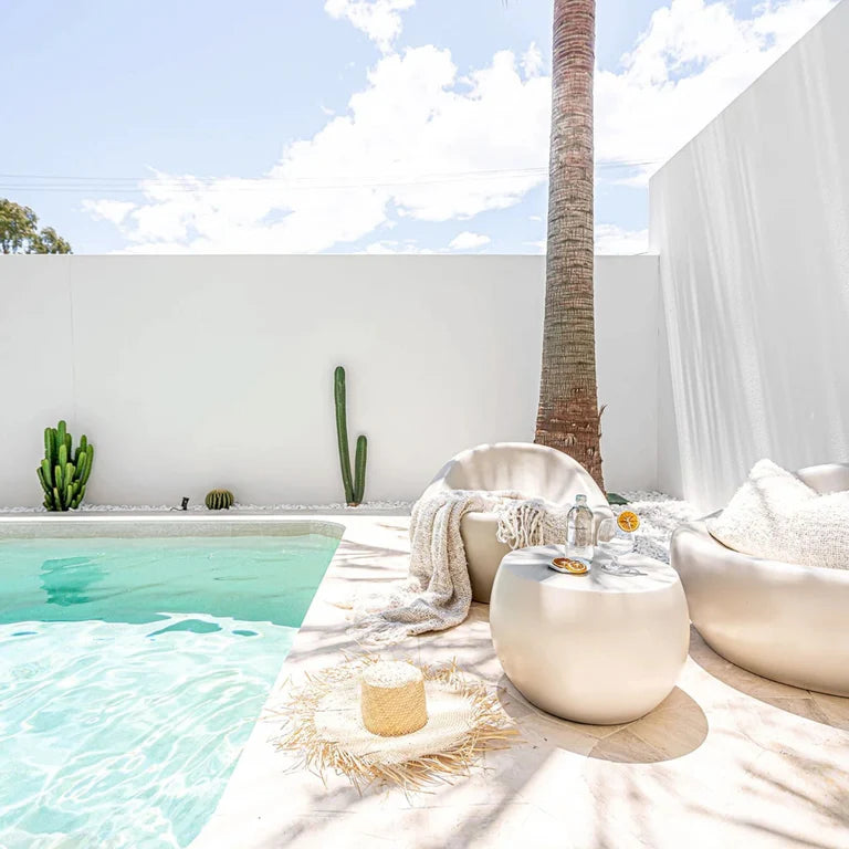 Santorini resin side table styled beside an outdoor lounge chair in a relaxed modern coastal pool side setting