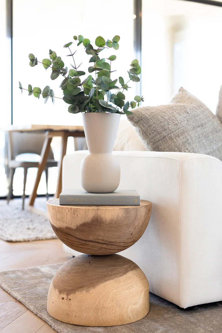 Mele Stool handcrafted from solid Munggur wood with unique grain, natural cracks, and organic form – doubles as a side or bedside table. Styled here as a side table in this coastal luxe home.