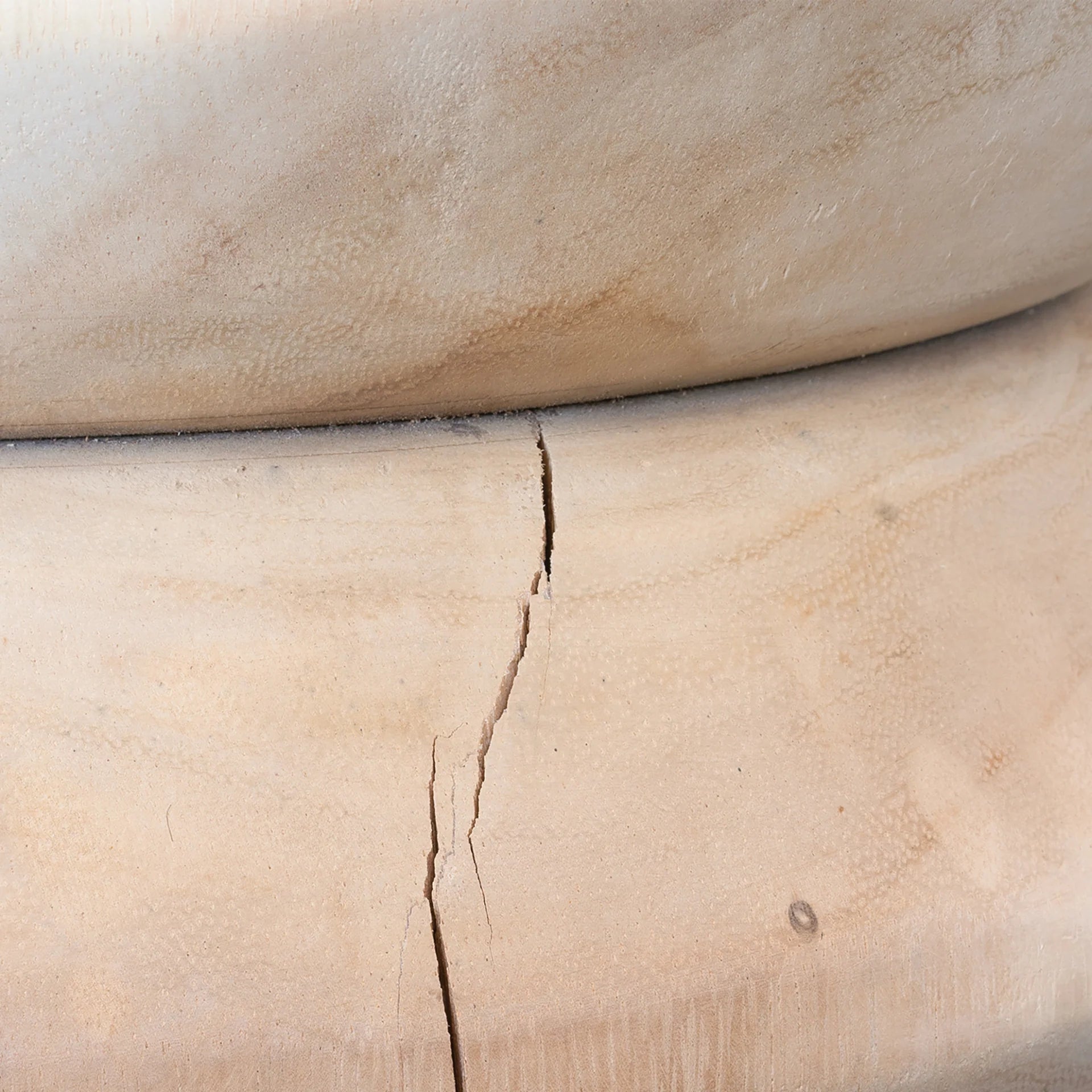 Rundu Table Lamp handcrafted from solid munggur wood with hand-carved textured grooves, showcasing natural wood variations and a soft ambient glow. Close up base.