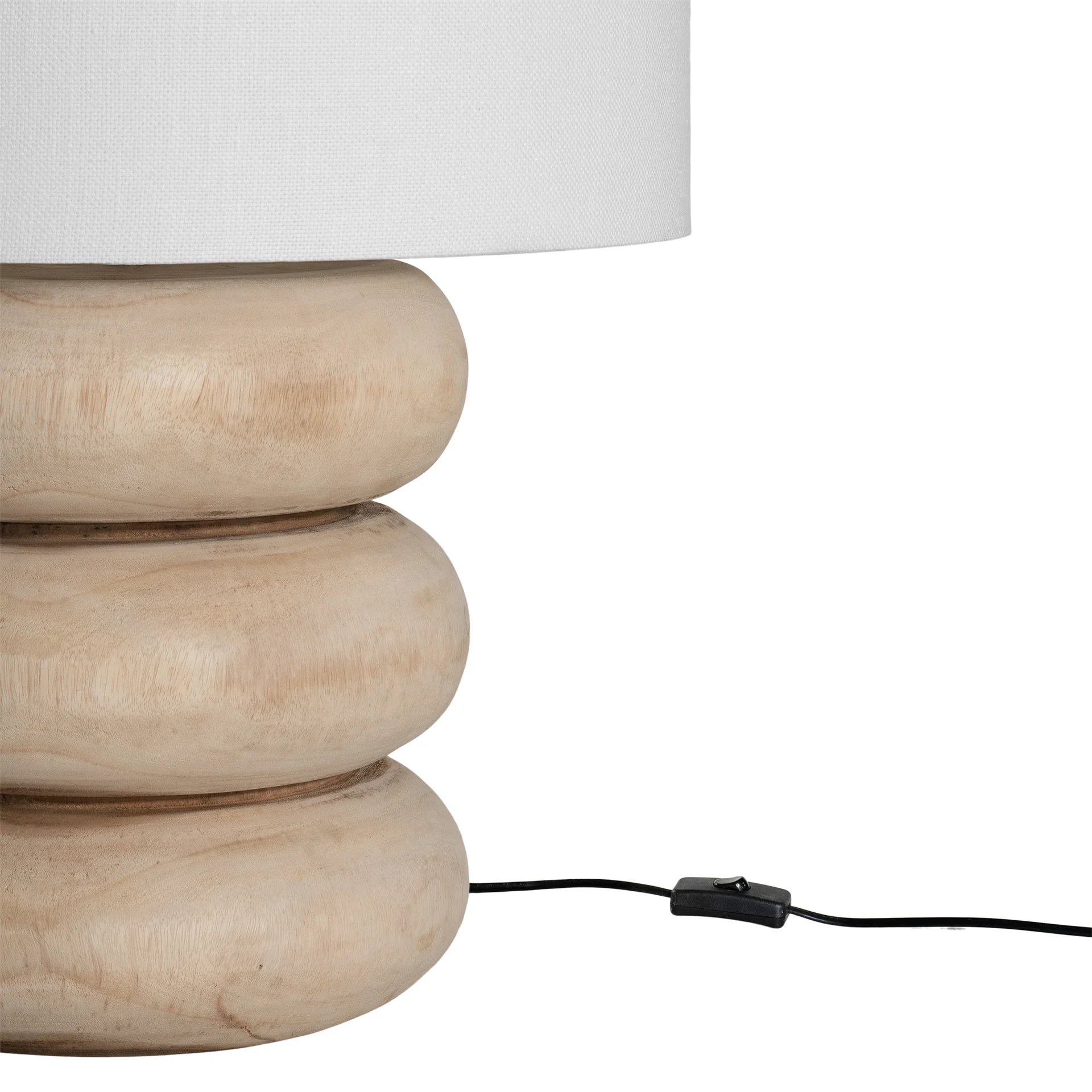 Rundu Table Lamp handcrafted from solid munggur wood with hand-carved textured grooves, showcasing natural wood variations and a soft ambient glow. Close up with cable 1.