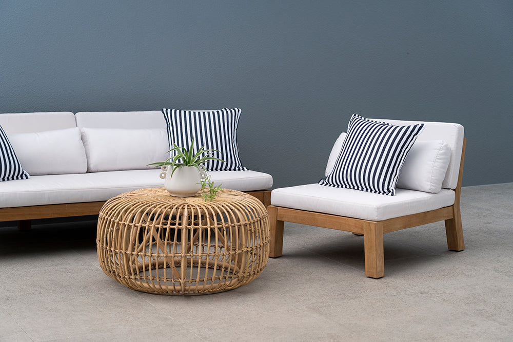 Bedarra teak outdoor three-seater sofa, styled seating detail with white cushions, striped accessories and a round woven coffee table