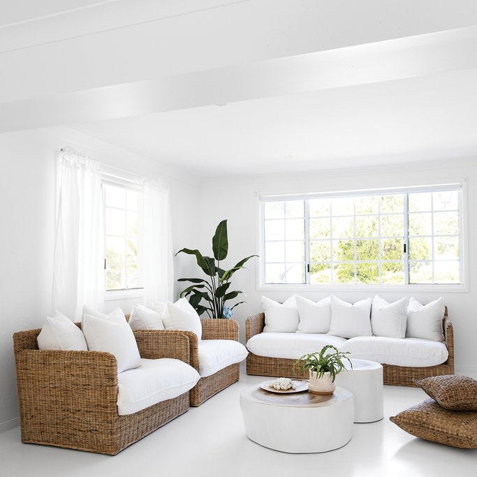 White Trunk Coffee Table styled with woven lounge chairs in a bright coastal living room