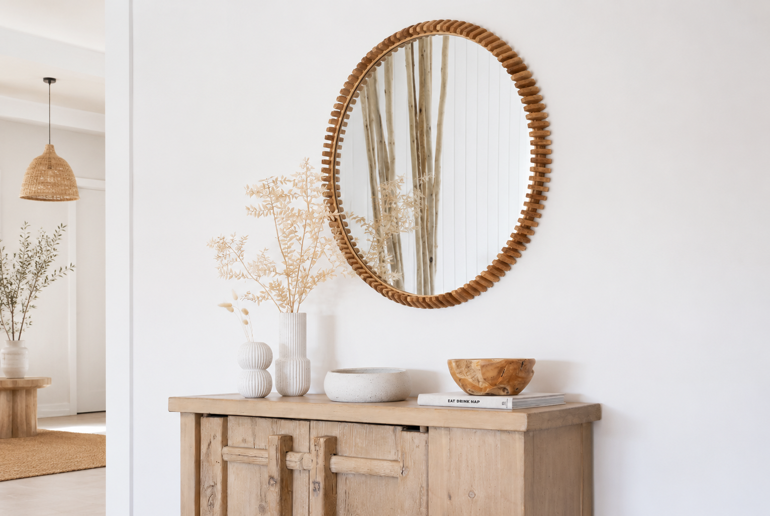 Round timber wall mirror styled above a rustic natural timber console with ceramic décor in a bright modern coastal Australian entryway.
