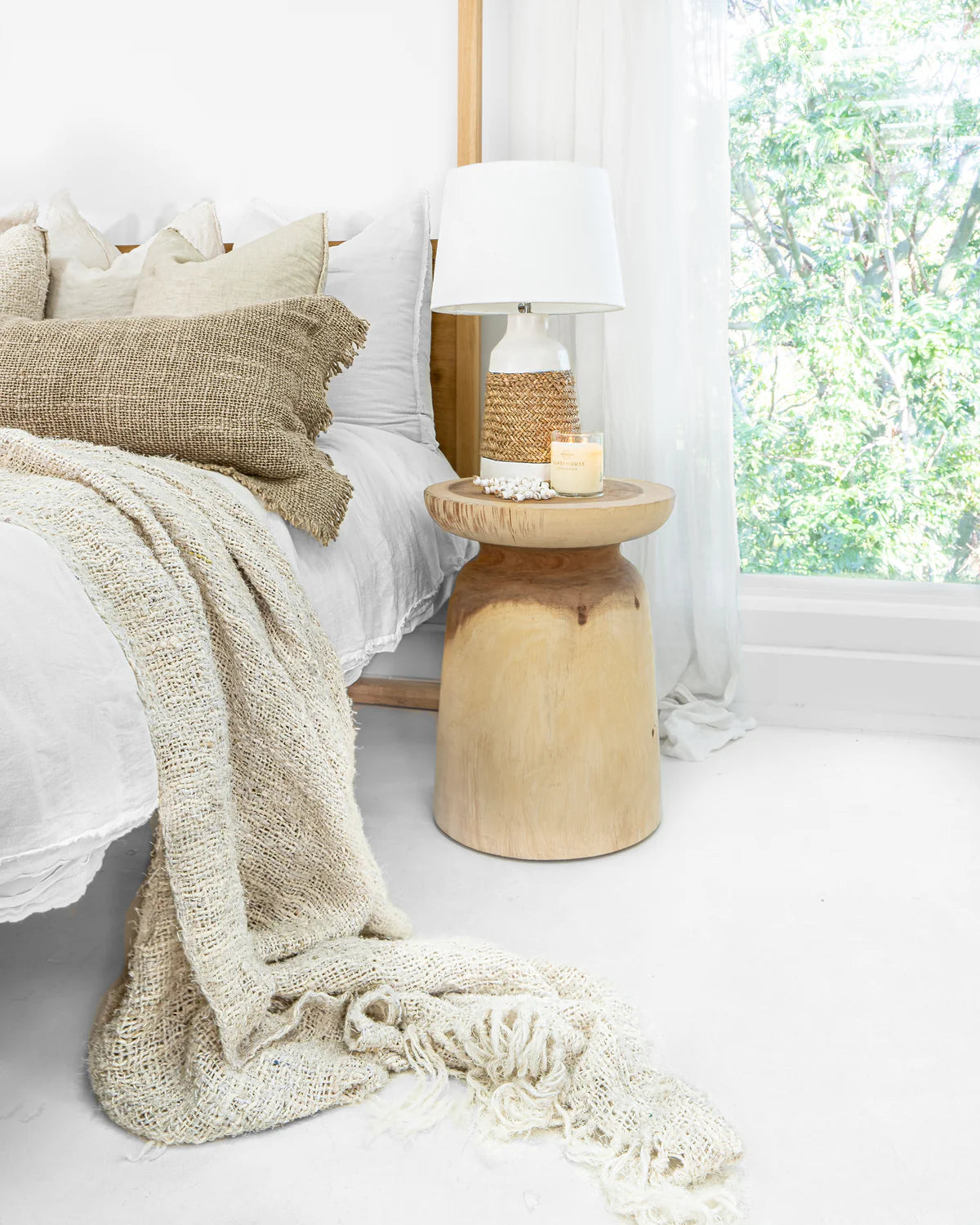 Akoni Side Table – hand-carved munggur wood side table with smooth sanded finish, unique natural design crafted using traditional techniques.  Styled beautifully in this bedroom.