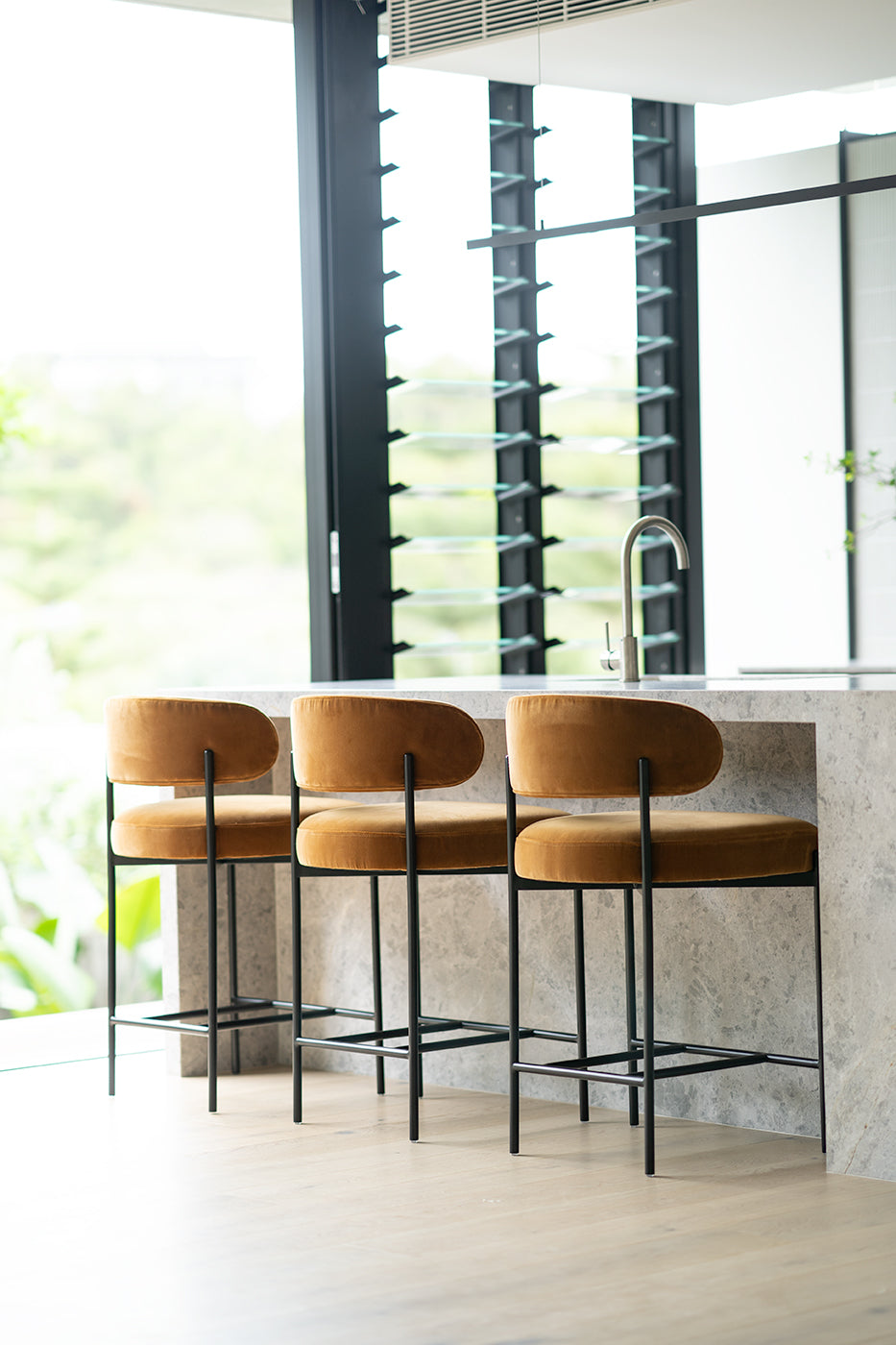 Fontaine Counter Stool with half-moon curved back and metal legs, upholstered in performance velvet in amber, modern Art Deco inspired counter stool for elegant interiors.  Modern kitchen style.