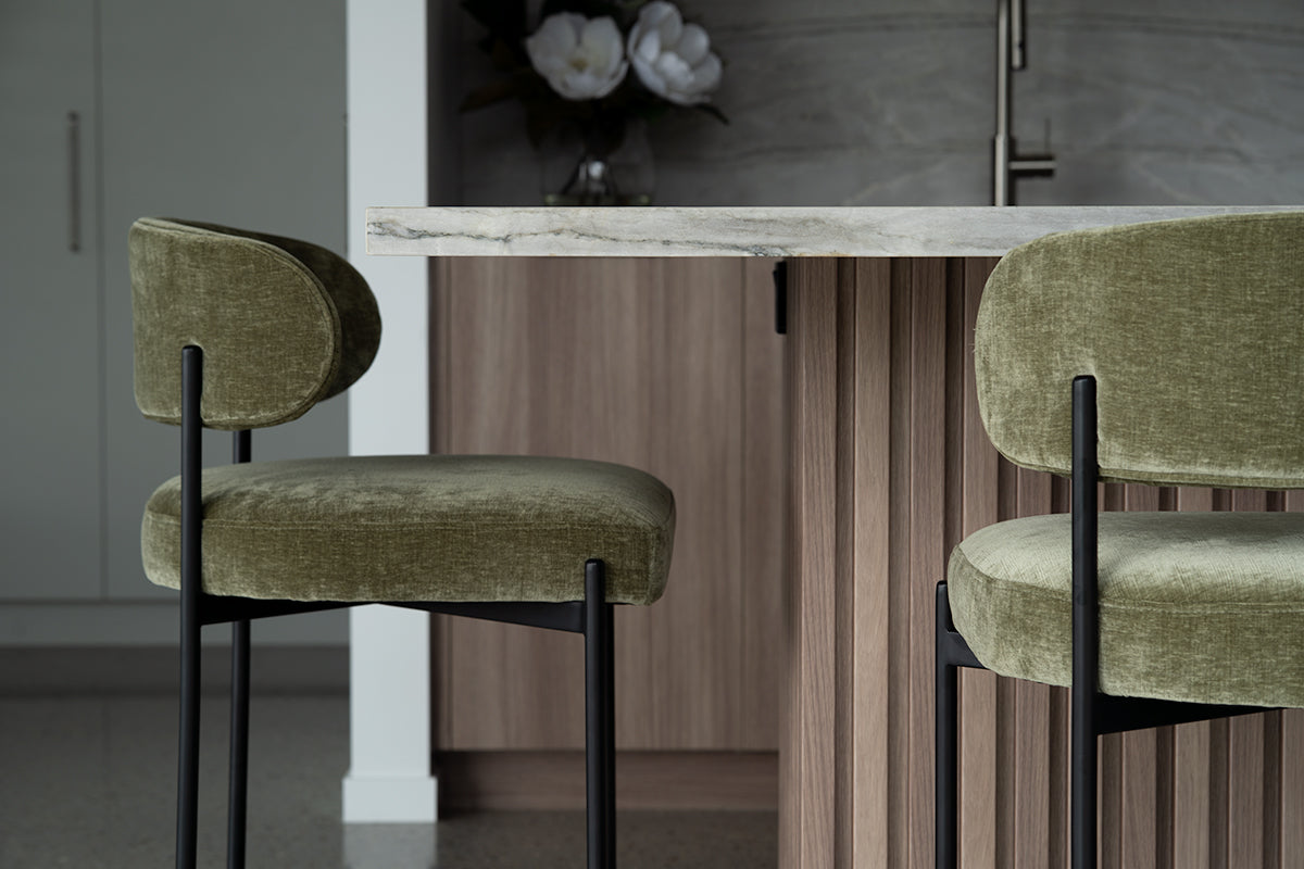 Fontaine Counter Stool with half-moon curved back and metal legs, upholstered in performance velvet in ivy, modern Art Deco inspired counter stool for elegant interiors.  Elegant kitchen, ivy green against walnut tones.