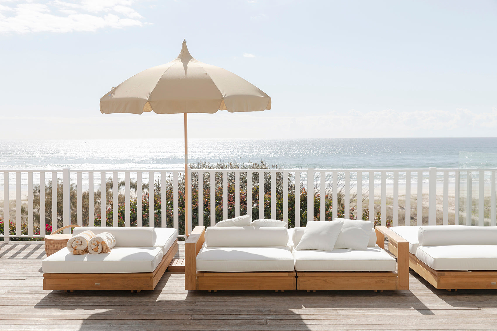 Harbour Island Double Outdoor Sun Lounger with Arms overlooking the ocean from a luxury coastal retreat.