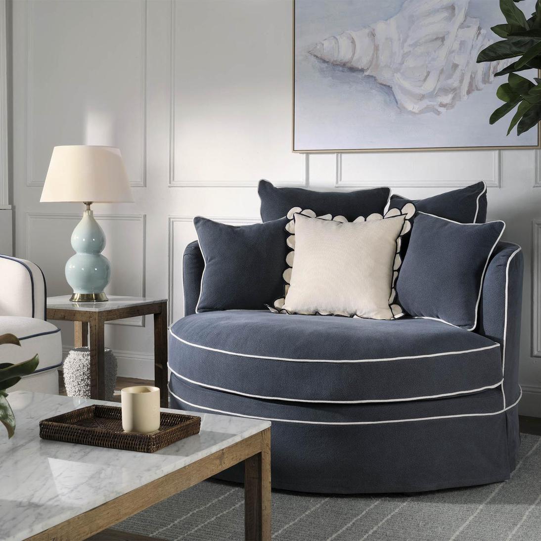 Noosa snuggle occasional chair in Navy with White Piping, styled with cushions and a side table in a living room