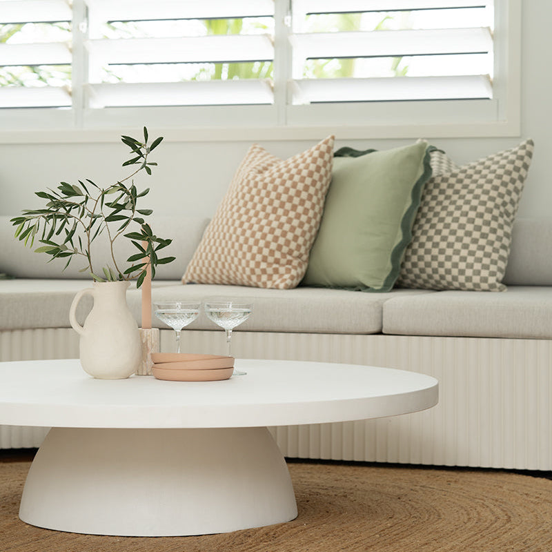 White microcement coffee table styled in a relaxed coastal living room with natural materials and soft neutral tones.