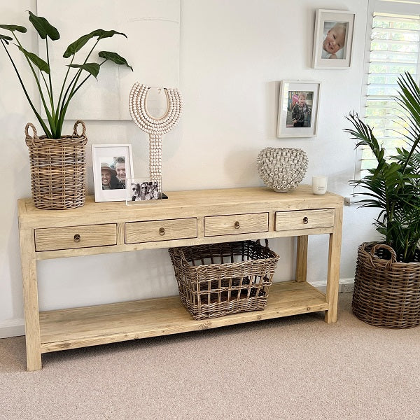 Reclaimed timber console table with four drawers and brass-look metal handles, handcrafted coastal furniture combining rustic and contemporary design for a warm, natural interior. Styled in a Modern coastal interior.