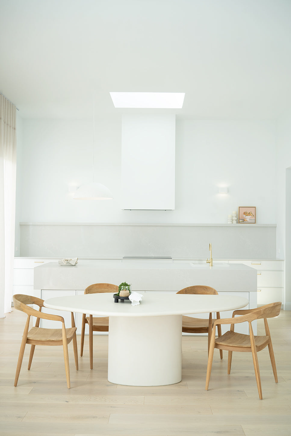 Saint Tropez Dining Table with ivory micro cement finish – modern coastal design with organic shape and refined matte texture.  Styled beautifully in this luxury coastal home.