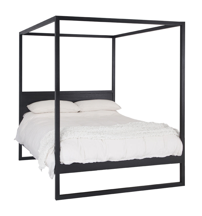 Strand four-poster bed in black lacquered European oak, angled product view with white bedding