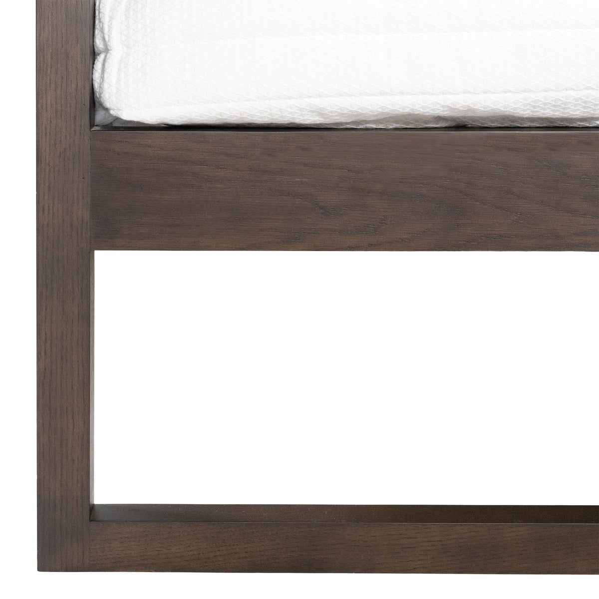 Close-up of the Strand bed walnut-coloured oak leg and frame join