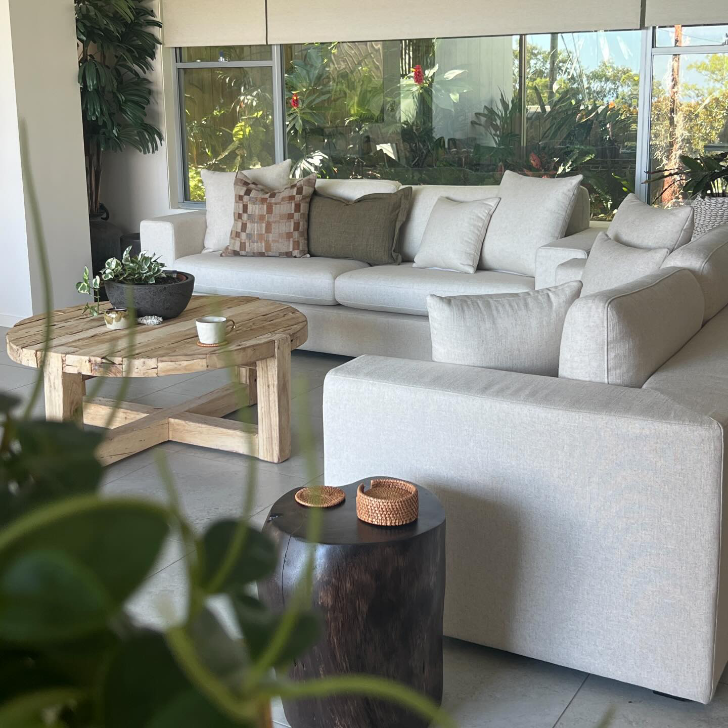 Round reclaimed timber coffee table in a relaxed coastal living space with soft neutral palette and layered textures