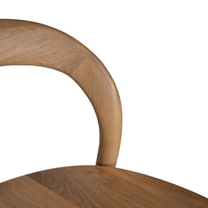 Loki Bar Chair in solid oak with natural finish, featuring sculptural minimalist design, rich wood grain, and black iron footrest for a modern touch. Backrest perspective.