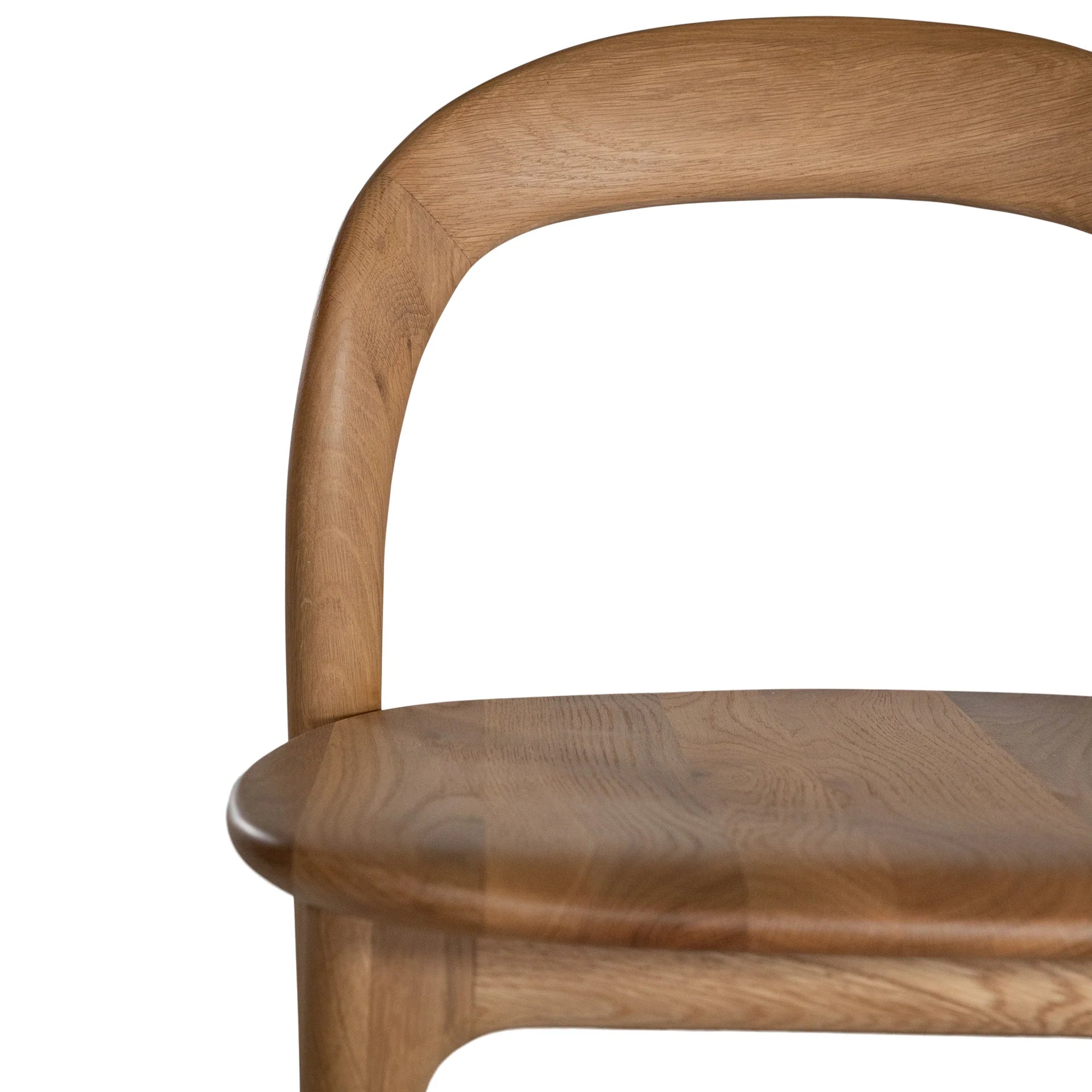 Loki Bar Chair in solid oak with natural finish, featuring sculptural minimalist design, rich wood grain, and black iron footrest for a modern touch. Close up perspective