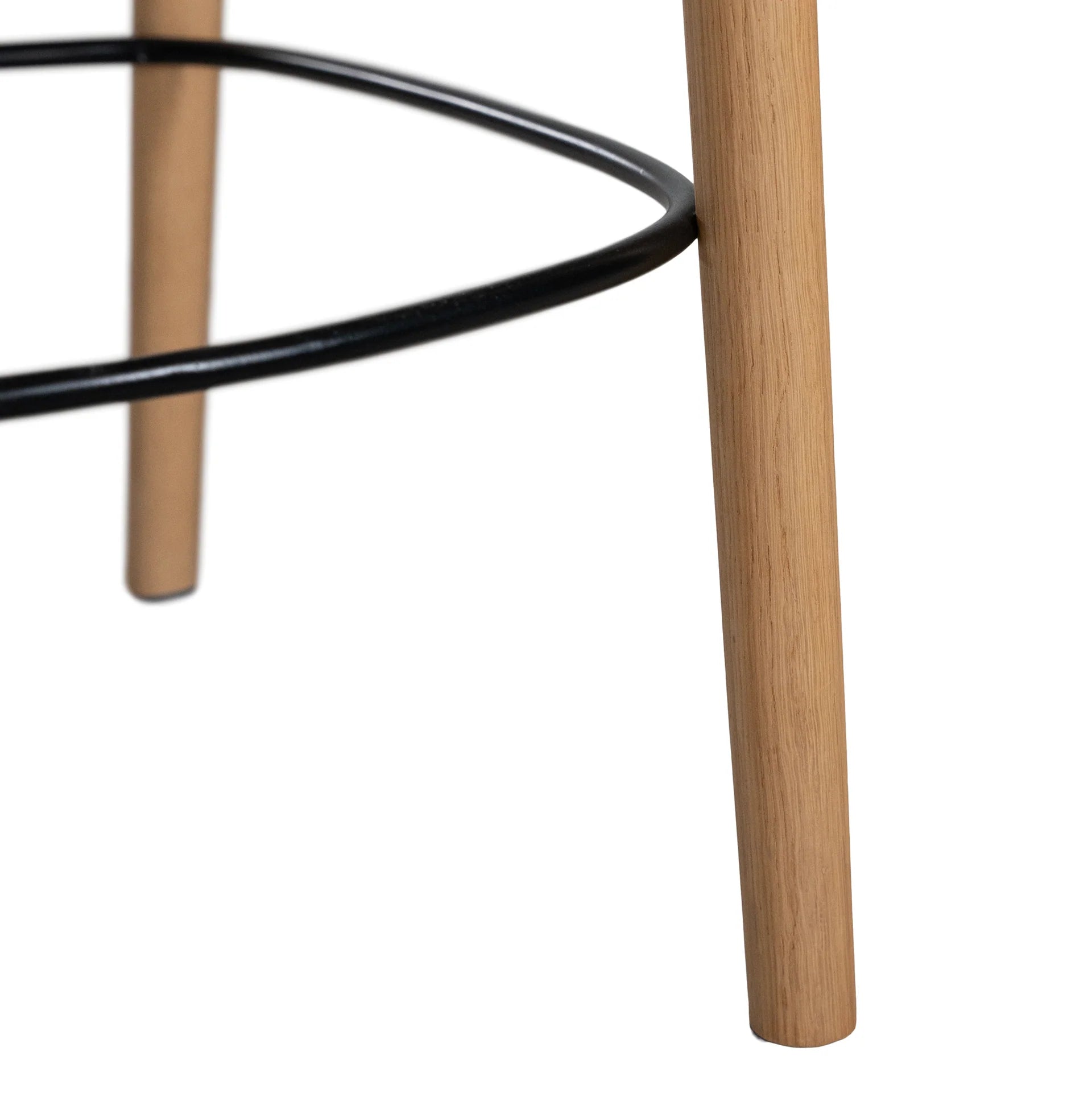 Loki Bar Chair in solid oak with natural finish, featuring sculptural minimalist design, rich wood grain, and black iron footrest for a modern touch. Footrest close up.