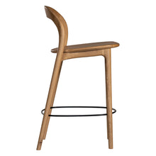 Load image into Gallery viewer, Loki Bar Chair in solid oak with natural finish, featuring sculptural minimalist design, rich wood grain, and black iron footrest for a modern touch. Side perspective.