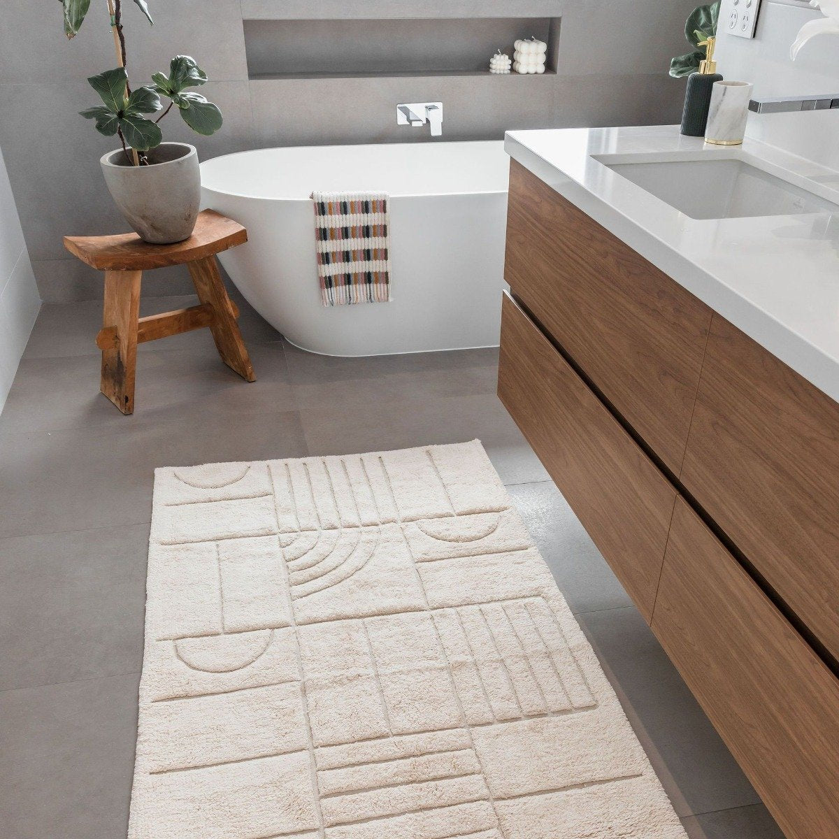 Natural cotton bath runner styled beneath timber vanity in relaxed contemporary bathroom