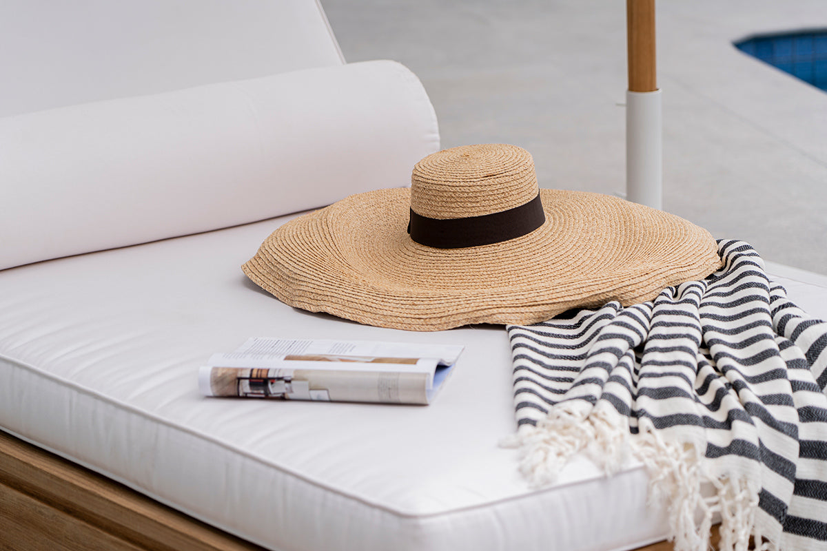 Harbour Island sun lounger cushion styled with a sunhat, book and striped throw